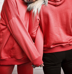 Woman and man standing in red sweatshirts. Burgundy hoodie on the model