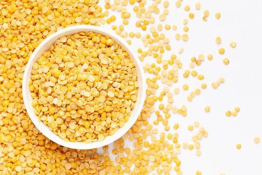 Close up of Organic arhar dal (Cajanus cajan) on a ceramic white bowl with the gradient background of split yellow arhar dal. Top view 