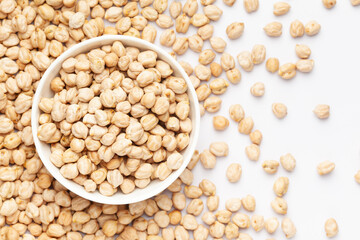 Close up of Organic chhole chana or Kabuli chana (Cicer arietinum) on a ceramic white bowl with the gradient background of whole white Bengal gram dal. Top view 