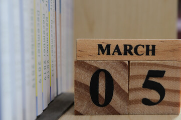 Day 5 of March month, Wooden cubes with date on the book shelf.
