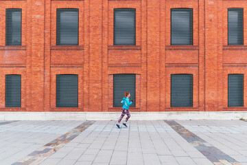 General shot of a sporty red-haired Caucasian female running outdoor