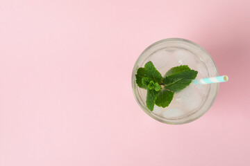 Glass of lemonade on pink background, top view