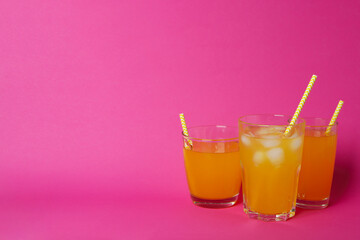 Glasses of orange soda on pink background