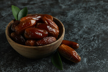 Wooden bowl of dates on black smokey background