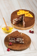 Honey cake with cherries on a white wooden background. Side view with a copy space for the text.