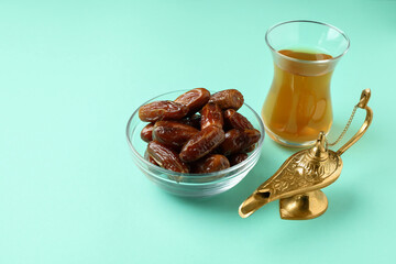 Glass of tea, Ramadan lamp and dates on mint background