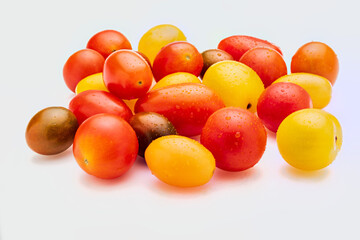 Colorful cherry tomatoes (red, garnet and yellow), fresh and raw. With water drops Isolated on white background.