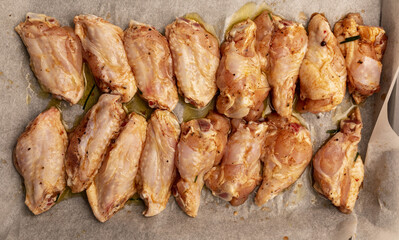 Raw chicken wings marinated with oil, pepper, chives, honey and spices on a baking tray.