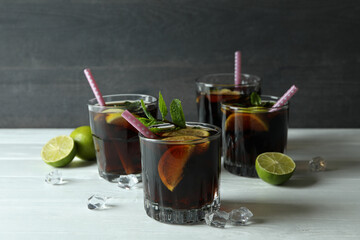 Cuba Libre cocktails on wooden table against dark background