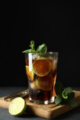 Board with glass of Cuba Libre against dark background