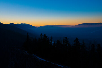 Obraz premium Colorful evening sky over Zakopane town, Poland. The winter is coming to the mountains. Clear sky filled with bright and vibrant colors. Selective focus on a mountain ridge, blurred background.