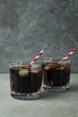 Glasses of cola on white textured table against gray background