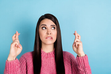 Portrait of nervous lady biting lip crossed fingers look interested empty space isolated on blue...