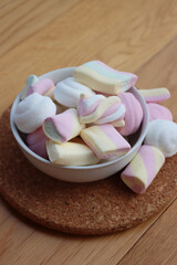 Colorful pink, white and yellow marshmallows in a bowl on wooden table