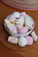 Colorful pink, white and yellow marshmallows in a bowl on wooden table