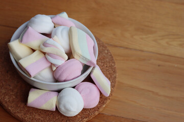 Colorful pink, white and yellow marshmallows in a bowl on wooden table