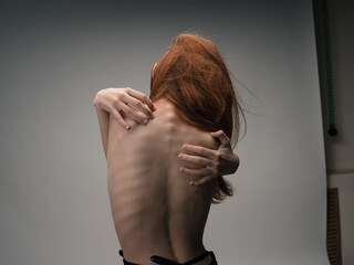 A thin woman touches herself behind her back with her hands with emotion model