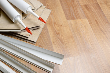 Set of items for PVC ceiling indoor works. Assembly adhesive bottles and PVC panels with plastic...