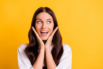 Portrait of positive charming girl hands palms on cheeks look empty space isolated on yellow color background