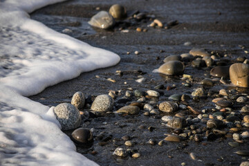Sea shore with stones and foam, pebble seascape. 