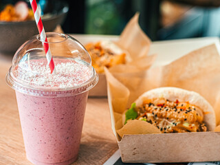 One pink fruit milk cocktail in plastic cup with white-red spiral pattern tube for milkshakes ...