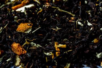 Dry black tea leaves with pieces of dried citrus peel, fruit and flowers. Close up tea background...