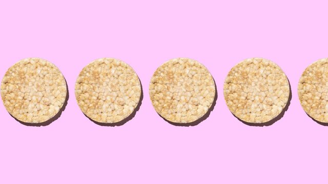 Stop motion animation of Gluten Free Round Rice Cakes moving from left to right on a pink background