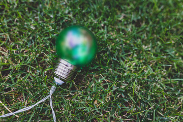 green light bulb on perfect green grass lawn, ecology and sustainability