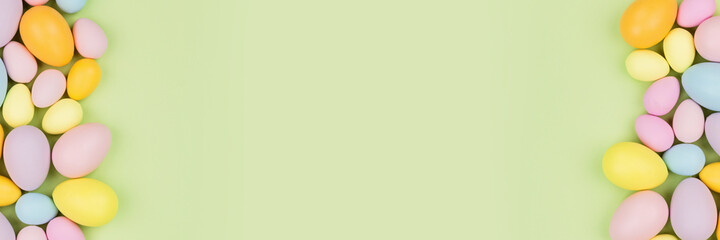 Stylish background with colorful easter eggs pastel colors isolated on green background. Horizontal...