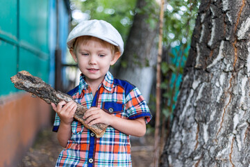 the child cuts wood with an axe and throws it into a pile