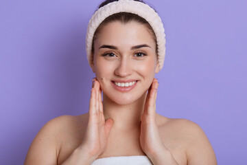 Beautiful face portrait of young woman touching her cheeks and smiling while looking directly at...