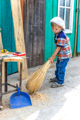 a small child helps to clean the yard in the yard of the house