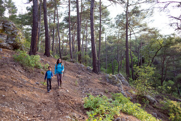 Naklejka na ściany i meble A woman walks with her son through the forest.