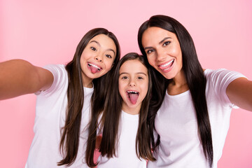 Photo portrait of smiling happy family mother and daughters talking selfie showing tongues isolated pastel pink color background