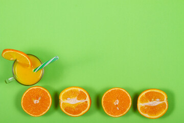 Glass of orange juice on green background with copy space
