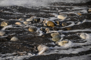 Sea shore with stones and foam, pebble seascape. 