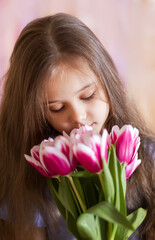 Little pretty girl holds a bouquet of pink tulips. Vertical