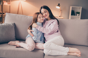 Obraz premium Portrait of attractive dreamy trendy cheerful girls sitting on divan embracing spending evening at house flat indoor