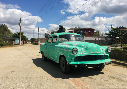 Classic Cuban car under repair on the outskirts of the town of Colón, Cuba. Green vintage car with peeling paint, no license plate and no brand on an esplanade.