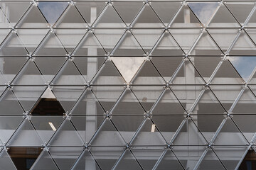 Modern building facade features a triangles pattern. Construction contemporary exterior made of grey iron triangle repetition where sky reflects into features an industrial architectural style. Malmo