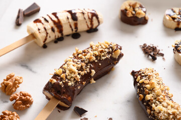 Frozen banana lollipops or lollies with walnuts sprinkles for kids on white. Easy homemade vegan sweets. Close up. © svetlana_cherruty