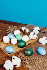 painted easter eggs on wooden board verbena flowers holiday blue background