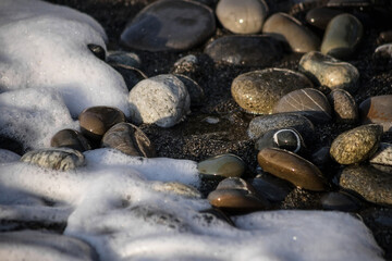 Sea shore with stones and foam, pebble seascape. 