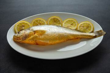 A fresh yellow croaker on a white plate
