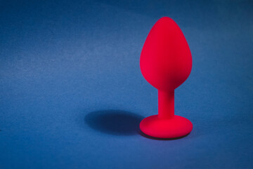 Beautiful smooth pink butt plug or buttplug, sex toy, on a blue background. Contrast photo of an...