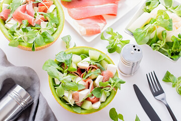 Summer mediterranean salad with ham and melon on white table top