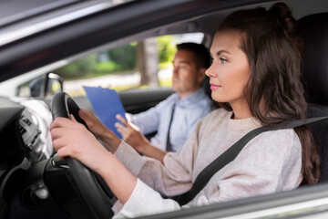 driver courses, exam and people concept - young woman and driving school instructor with clipboard talking in car