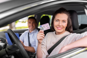 driver courses, exam and people concept - young woman with license and driving school instructor...