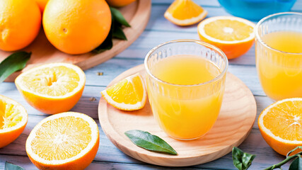 Two glasses of fresh juice, fruit squeezer and ripe fresh oranges on blue wooden table top, fresh orange juice making, top view