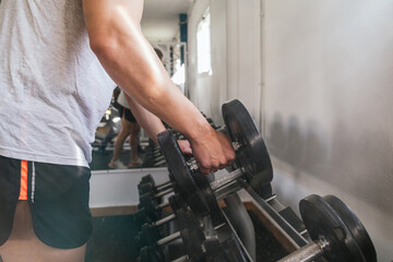 Hand gripping a dumbbell, on a dumbbell bench. Gym. Sports concept.